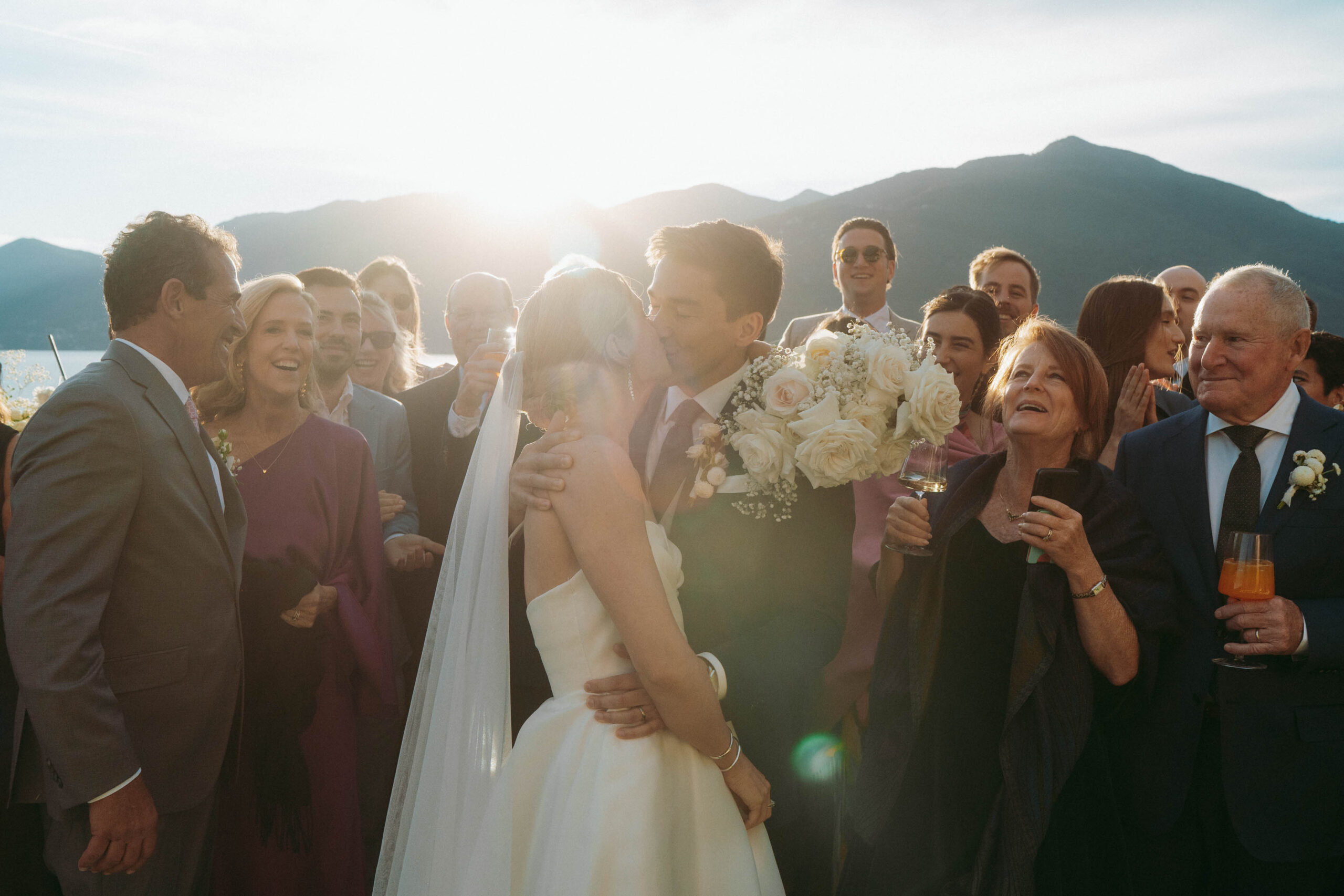 A romantic group photo with a wedding couple kissing at their wedding at Villa Porta